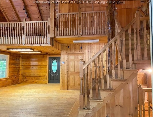 staircase featuring wooden walls, wood finished floors, and a high ceiling