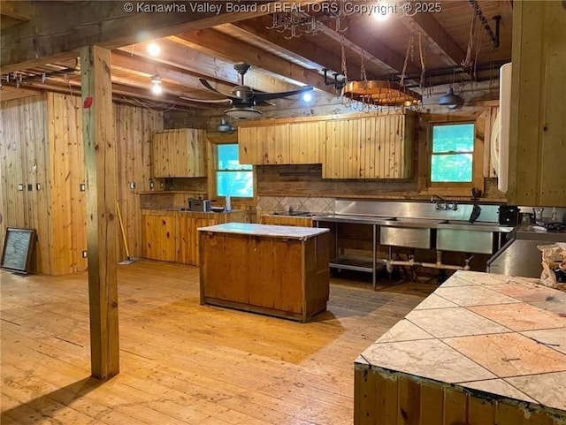 kitchen with light wood finished floors, ceiling fan, wood walls, and a wealth of natural light