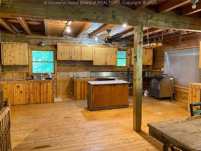 kitchen featuring light wood-type flooring, beam ceiling, a kitchen island, tasteful backsplash, and wood walls