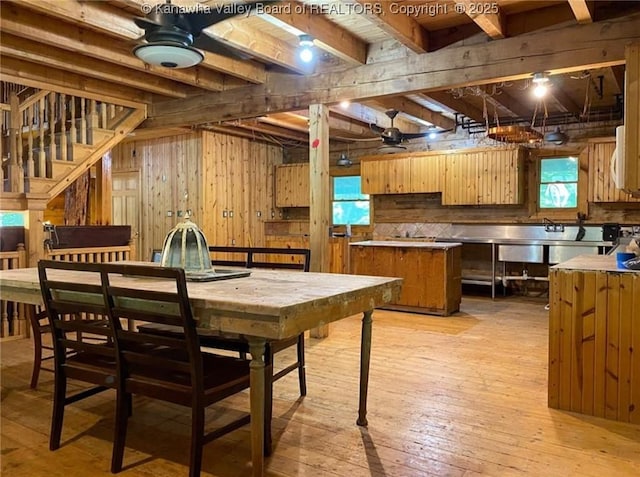 kitchen with tasteful backsplash, wooden walls, beam ceiling, light wood-style flooring, and a ceiling fan