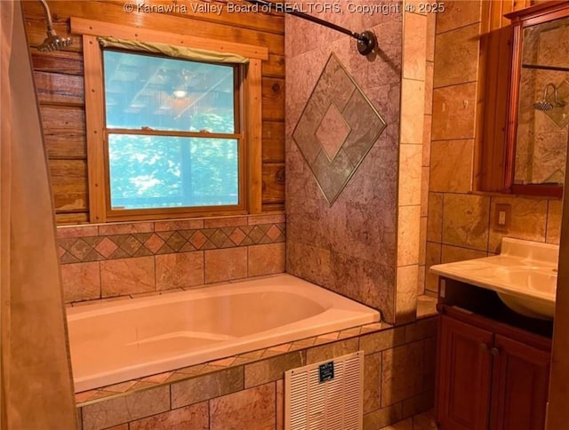 bathroom with visible vents, tiled tub, and vanity