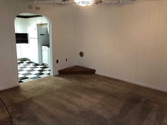 carpeted spare room with tile patterned floors, a decorative wall, and arched walkways