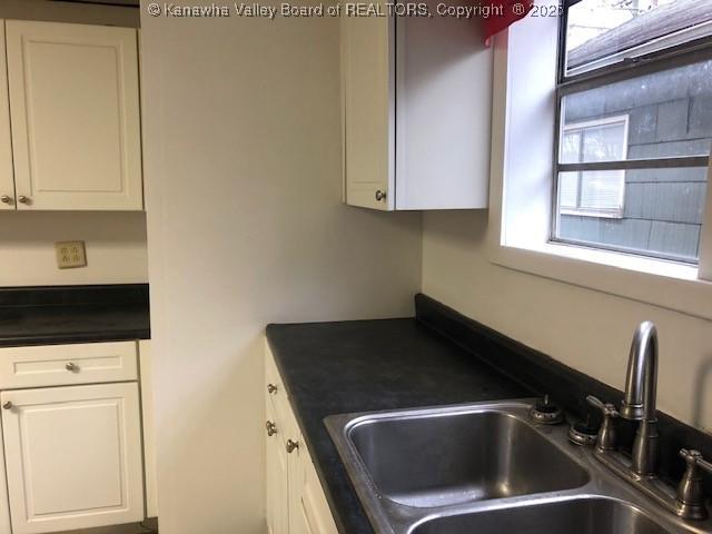 kitchen with white cabinetry, dark countertops, and a sink