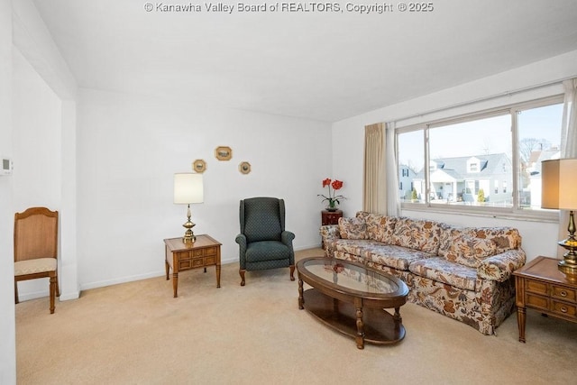 living area featuring baseboards and light carpet