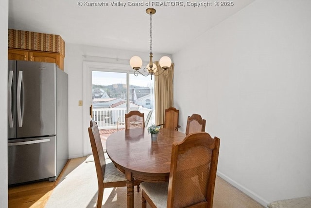 dining room featuring a notable chandelier, baseboards, and light wood finished floors