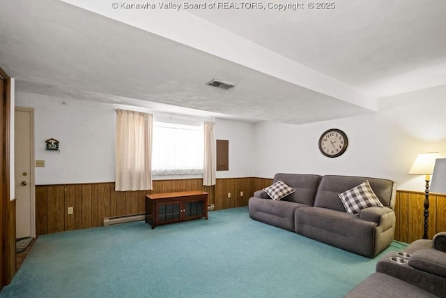 carpeted living room featuring baseboard heating, visible vents, a wainscoted wall, and wood walls