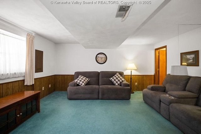 living area with a wainscoted wall, visible vents, electric panel, carpet, and wood walls