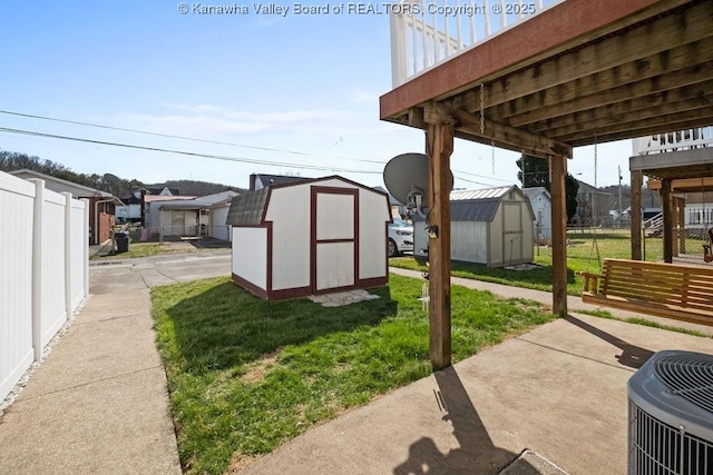 view of yard with a shed, cooling unit, an outdoor structure, and fence