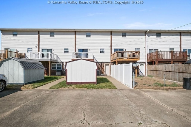 rear view of house featuring an outbuilding, a storage unit, and central AC