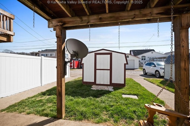 view of yard featuring an outbuilding, a storage unit, and fence