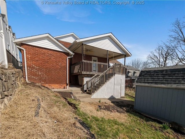 exterior space with an outbuilding, a shed, ceiling fan, stairs, and brick siding