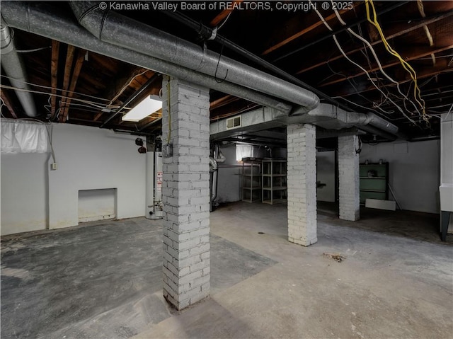 unfinished basement featuring visible vents and gas water heater