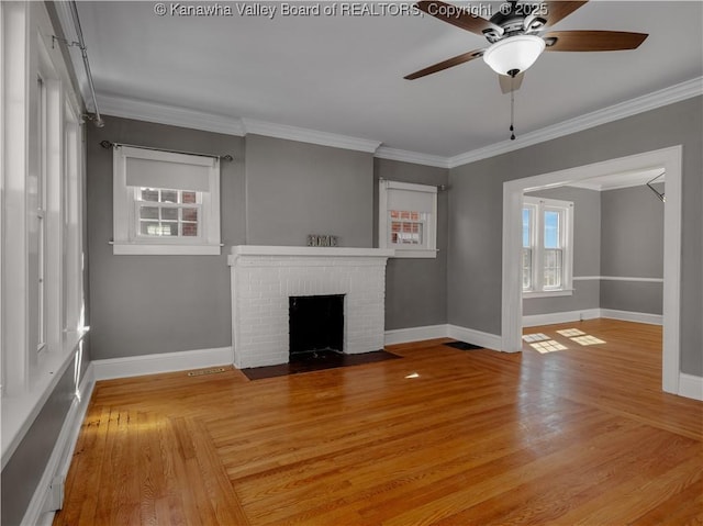 unfurnished living room featuring a brick fireplace, wood finished floors, and crown molding