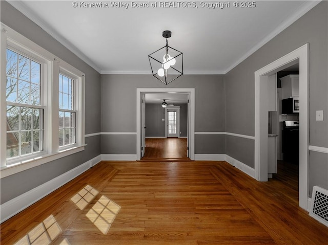 unfurnished dining area featuring baseboards, wood finished floors, visible vents, and ornamental molding