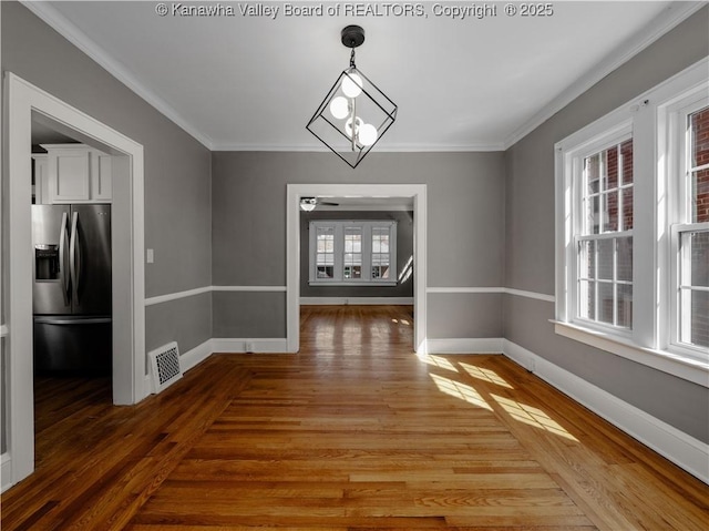 unfurnished dining area featuring visible vents, a notable chandelier, ornamental molding, light wood-style floors, and baseboards