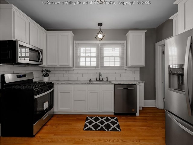 kitchen featuring a sink, light wood-type flooring, appliances with stainless steel finishes, and white cabinetry