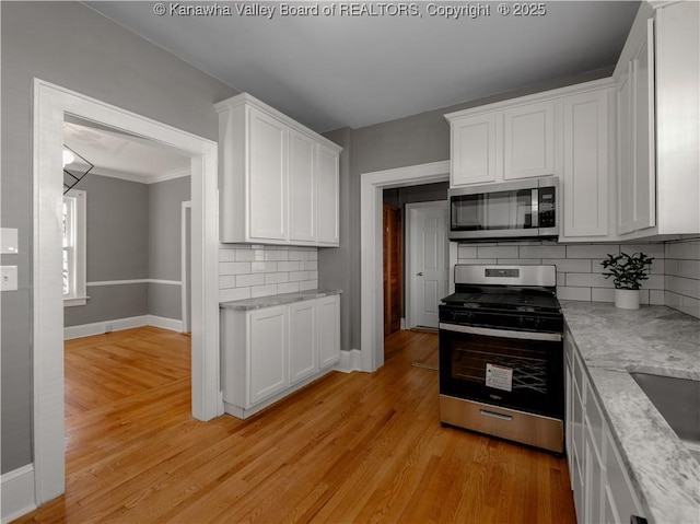 kitchen featuring white cabinets, baseboards, light wood finished floors, and stainless steel appliances