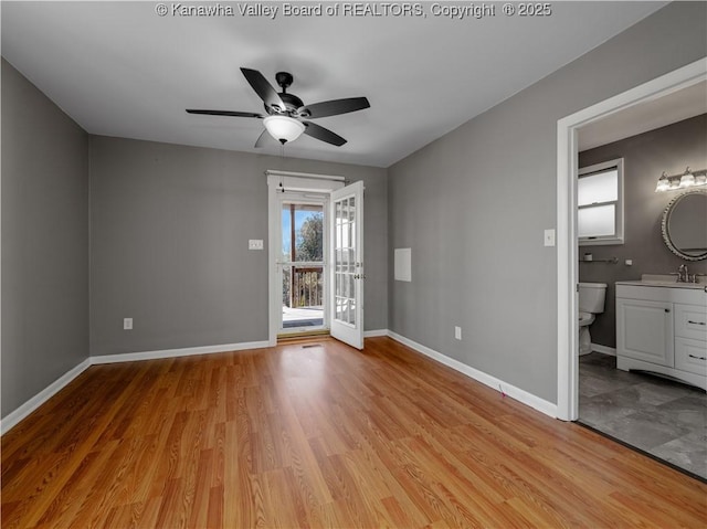 unfurnished bedroom with access to exterior, baseboards, light wood-style floors, and a sink