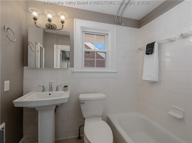 bathroom with shower / tub combination, toilet, tile walls, and a sink