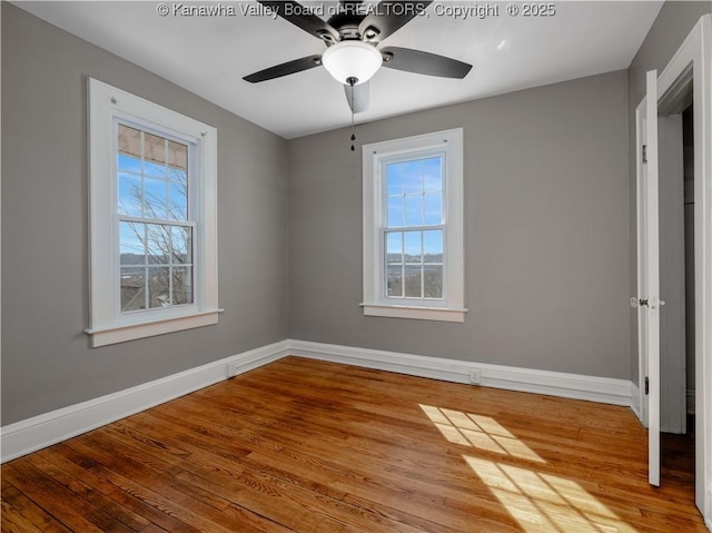 unfurnished bedroom with multiple windows, wood finished floors, and baseboards