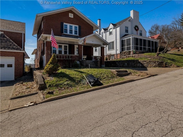 view of front of house with a porch, brick siding, a sunroom, and a front lawn