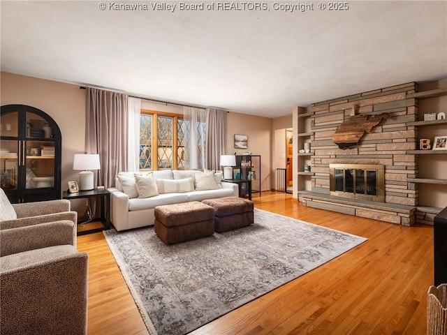 living room featuring light wood-style floors and a stone fireplace