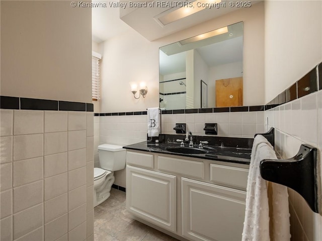 full bath featuring vanity, tile patterned flooring, wainscoting, tile walls, and toilet