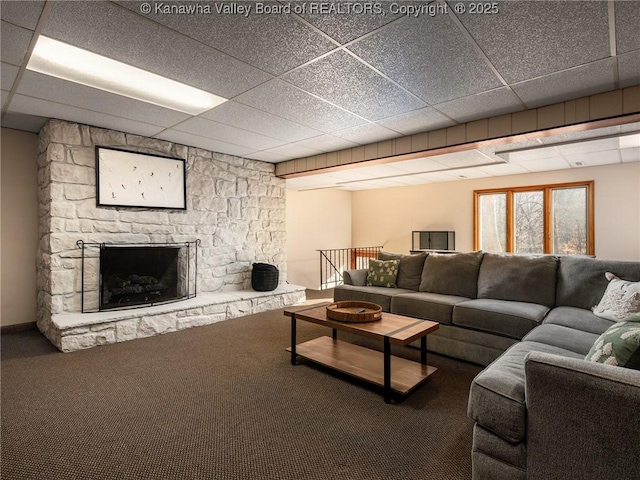 carpeted living room featuring a stone fireplace and a paneled ceiling