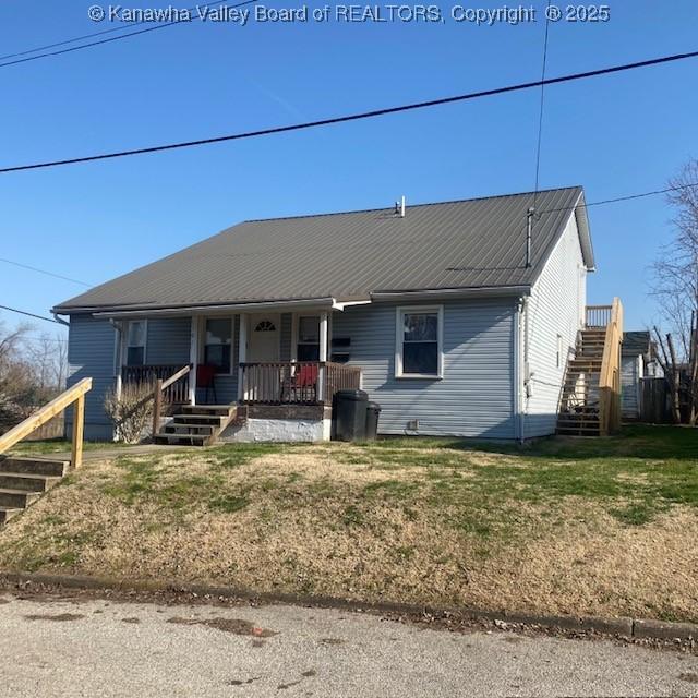 view of front of property with stairs, a porch, a front lawn, and metal roof