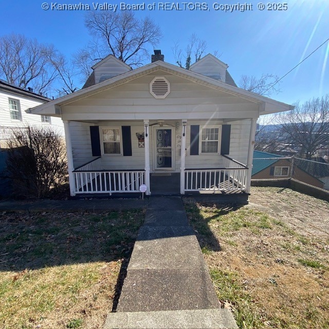 bungalow-style house with covered porch, a chimney, and fence