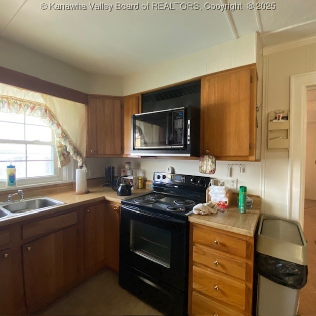 kitchen featuring a sink, black appliances, brown cabinetry, and light countertops