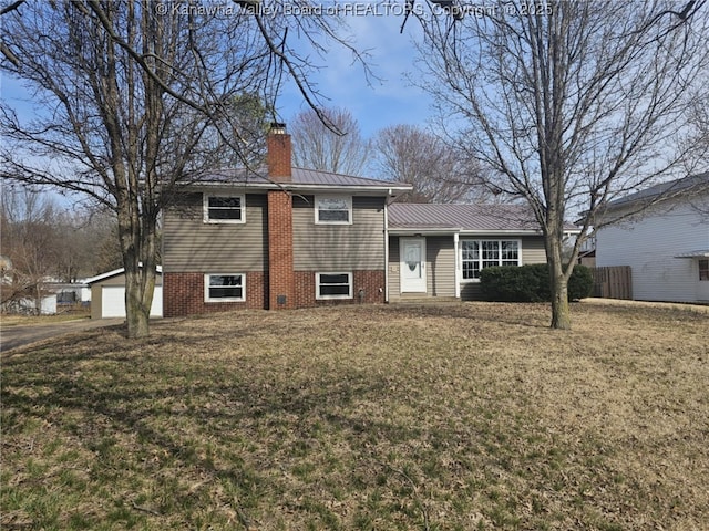 split level home with a standing seam roof, a chimney, a front lawn, a garage, and metal roof