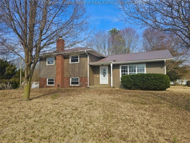 split level home with metal roof, a chimney, and a front yard