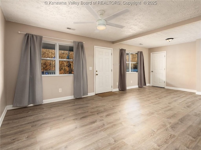 spare room with ceiling fan, visible vents, baseboards, and wood finished floors