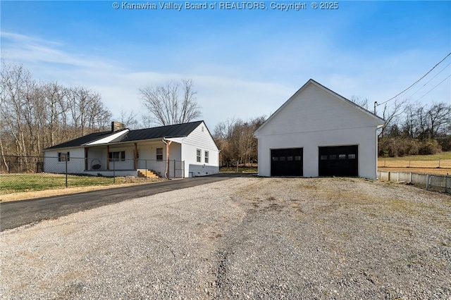 view of side of home featuring a garage, an outbuilding, and fence