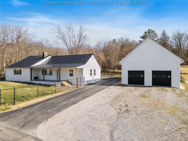 view of front of house with an outbuilding, a fenced front yard, a detached garage, metal roof, and a chimney