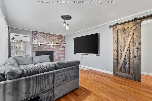 living area with a barn door, baseboards, wood finished floors, and a fireplace