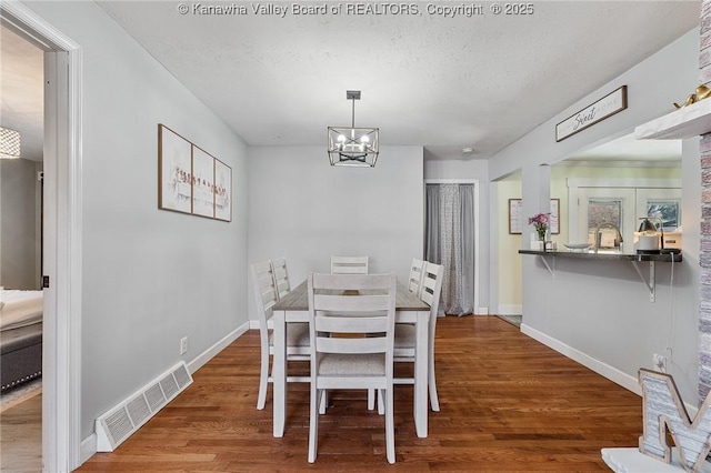 dining area featuring visible vents, baseboards, and wood finished floors