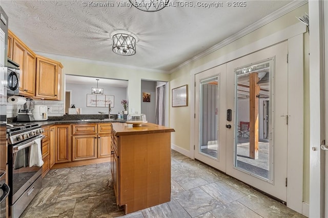 kitchen with stainless steel range with gas cooktop, ornamental molding, french doors, wood counters, and a sink