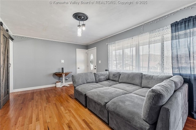 living area with a barn door, light wood-style flooring, and baseboards