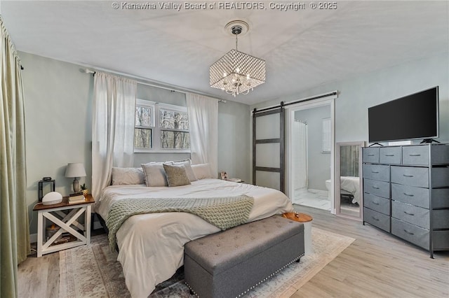 bedroom with a barn door, a chandelier, and light wood finished floors