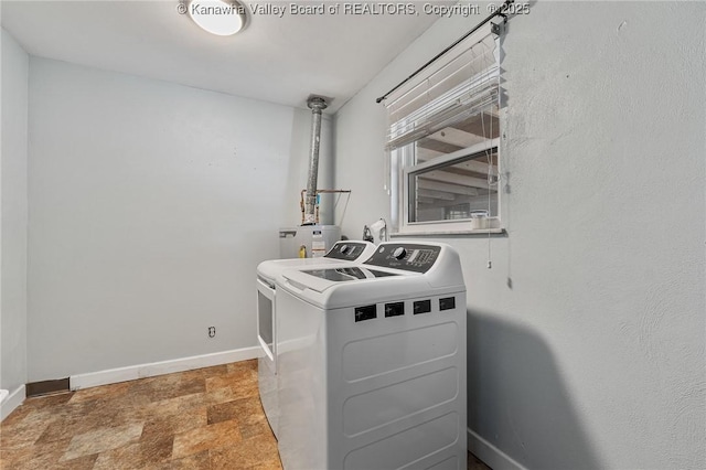 laundry area featuring washer and clothes dryer, stone finish flooring, water heater, baseboards, and laundry area