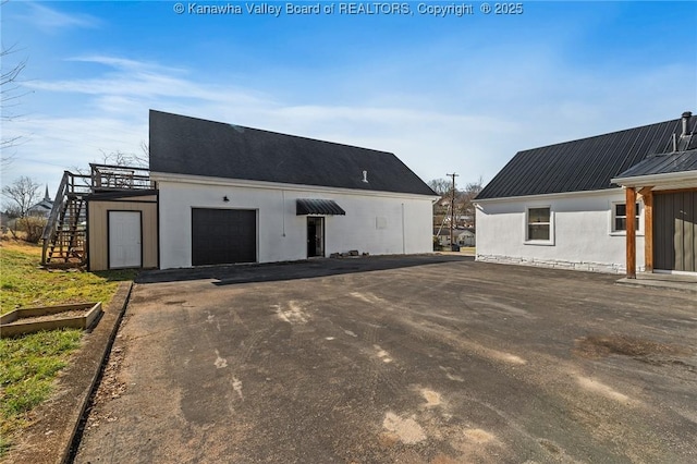 view of outbuilding featuring stairs, aphalt driveway, and a garage