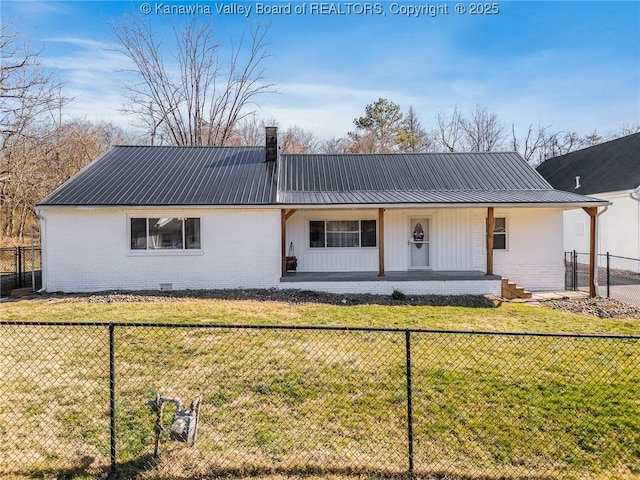 view of front of home with a fenced front yard, a front yard, metal roof, brick siding, and a chimney