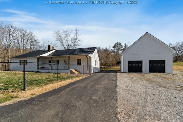 exterior space with an outbuilding, a detached garage, fence, metal roof, and a chimney