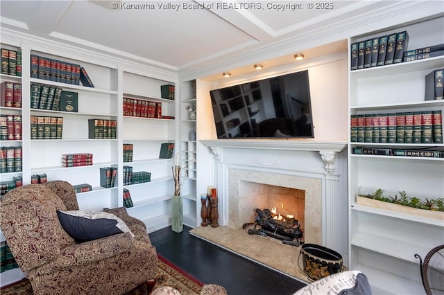 living area featuring a premium fireplace, wood finished floors, and ornamental molding