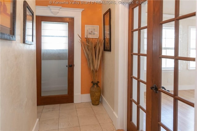 hallway featuring tile patterned flooring, plenty of natural light, french doors, and baseboards