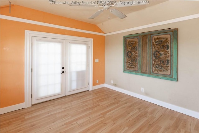 spare room with a ceiling fan, vaulted ceiling, light wood-style floors, and baseboards