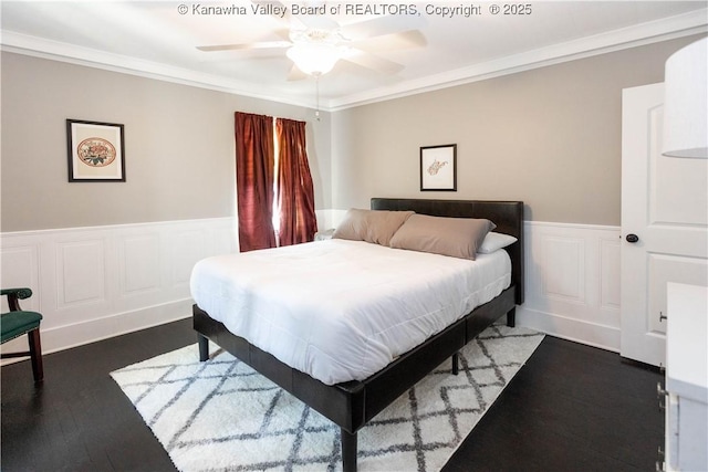 bedroom with ceiling fan, ornamental molding, wood finished floors, and wainscoting