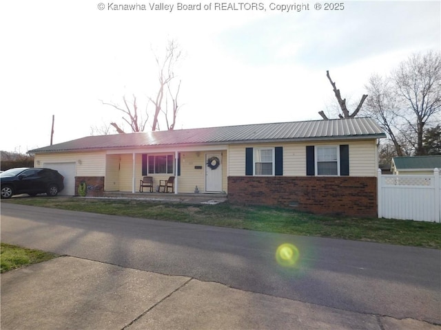 single story home featuring brick siding, an attached garage, metal roof, and fence